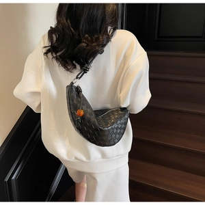 Detail of black woven leather half-moon bag with knot strap and orange bead accent