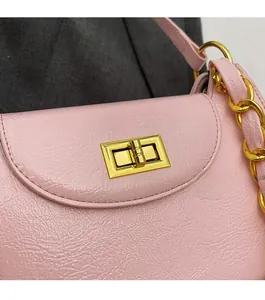 Detail of golden metal swivel lock on pink pebbled leather bag with chain strap