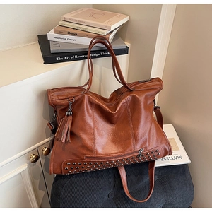 Detail of vintage brown tote bag with metal rivets, leather tassels and stylish long handles