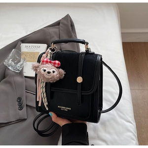 Detail shot of the black leather backpack with metal buckle and plush toy charm