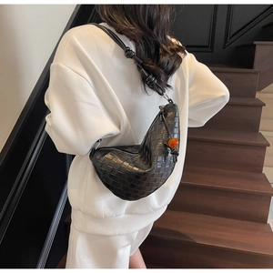 Close-up of black woven crescent bag with knot detail and amber bead on a model