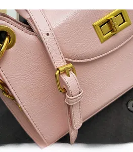 Detail of pink textured leather bag featuring golden lock and adjustable shoulder strap