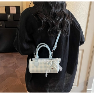 Détail du sac cylindre à carreaux bleus avec nœud en dentelle et chaîne de perles