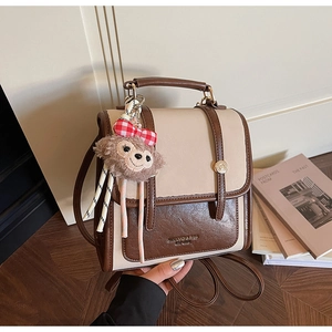 Detailed close-up of beige and brown retro backpack with plush bear charm and metal buckle
