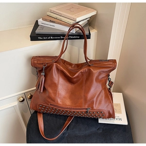 Detail of vintage brown tote bag showing soft leather texture and stylish tassel charm