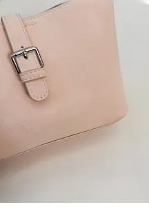 Close-up of pink textured leather bag featuring silver metal buckle and stitching