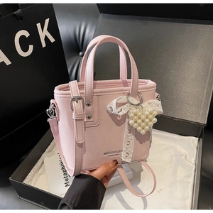 Detail der rosa Beuteltasche mit Perlen-Herzanhänger und Spitzenschleife in Box