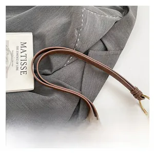 Close-up of brown leather bag with large bronze metal rings and decorative studs