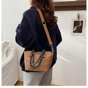 Detailed shot of a brown checkered tote bag with woven handles on a fashion model