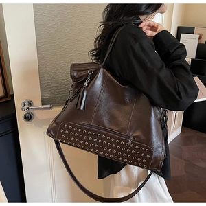 Detail of vintage brown leather tote bag showing silver rivets and fringe tassel detail