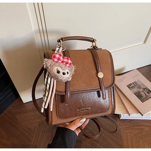 Detail of vintage brown contrast backpack with adjustable straps and plush bear charm