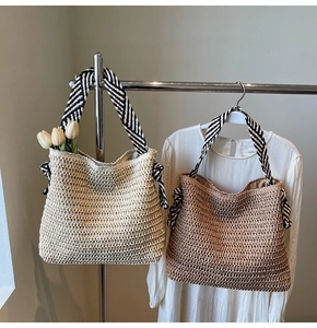 Detail of straw woven tote bags in beige and brown with striped canvas handles