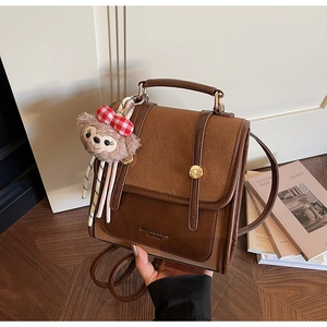 Detail view of brown vintage backpack featuring metal buckles and a cute plush bear charm