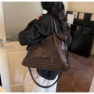 Detail of vintage brown tote bag with silver rivets and adjustable crossbody strap