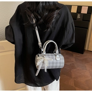 Détail d'un sac Boston à carreaux argentés avec nœud en dentelle et perles fines