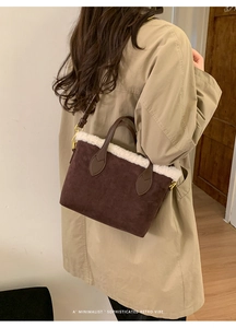 Detail of dark brown faux suede bucket bag with white plush trim and golden hardware