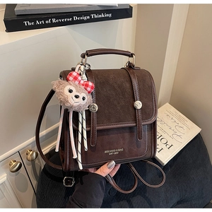 Close-up of retro brown faux leather backpack with vintage metal lock and plush toy charm