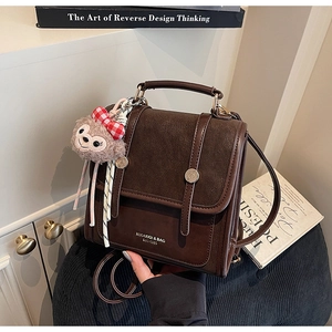 Close-up of retro brown contrast backpack with plush charm and polished metal buttons