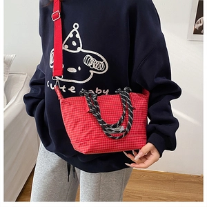 Close-up of red plaid canvas bag with braided handles and adjustable shoulder strap