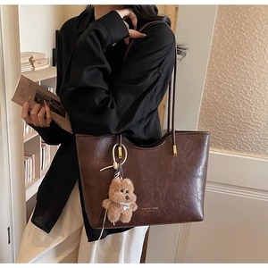 Detail view of large dark brown retro tote bag with plush bear charm and pearls