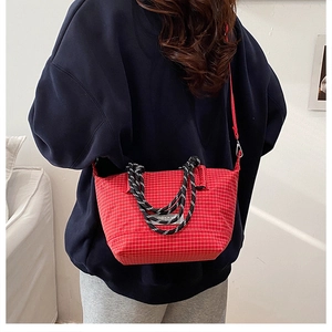 Detail of red plaid tote bag with rope handles and adjustable crossbody strap