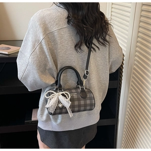 Femme portant un sac cylindrique à damier avec un nœud en dentelle et perles en extérieur