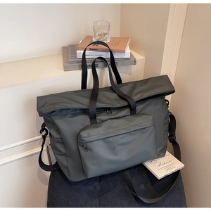 Détail d'un grand sac cabas gris sur une chaise en velours avec poche avant et bandoulière