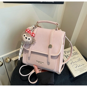 Detail of light pink backpack featuring a flap magnetic buckle and a plush charm