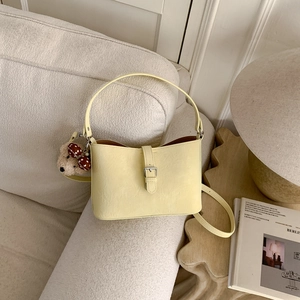 Detail of light yellow PU leather bucket bag with silver buckle and cute plush charm