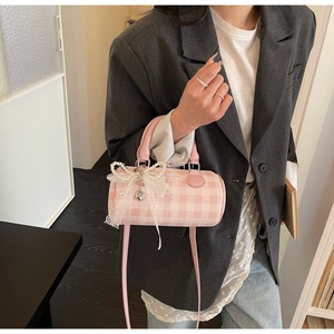 Vue détaillée du sac cylindrique à carreaux rose et blanc avec nœud en dentelle de perles