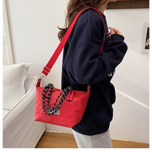 Detail view of red checkered crossbody bag with woven handles and wide canvas shoulder strap