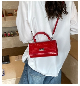 Model view showing red crocodile pattern crossbody bag with silver clasp in a cafe setting