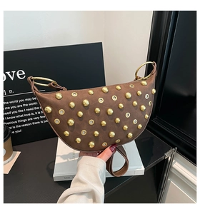Detail of brown saddle bag featuring gold studs, eyelets and large metal ring handle