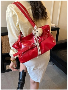 Fashionable red patent leather tote bag with straps and charm shown on a model