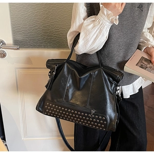 Close-up of black leather tote bag featuring silver studs and stylish tassel detail