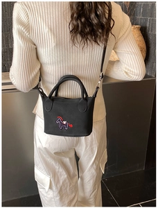 Detail einer Mini-Eimertasche in Schwarz mit bunter Pferdestickerei am Modell
