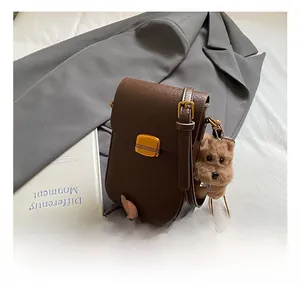 Detail of a brown vintage crossbody phone bag with gold metal buckle and cute dog charm