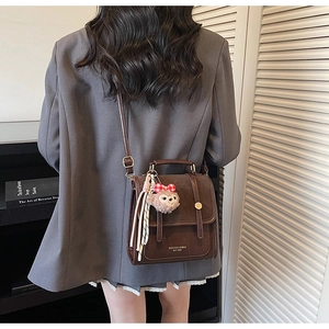 Detail view of a vintage brown leather backpack with a plush rabbit pendant and strap