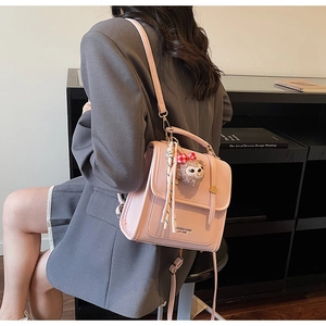 Detail shot of the pink leather crossbody bag with metal buckle and plush bear charm