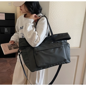 Détail du sac cabas noir en nylon avec large bandoulière et poche zippée porté