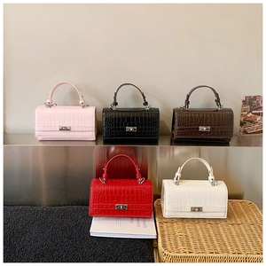 Close-up of crocodile pattern handbags in five colors featuring silver metal twist locks