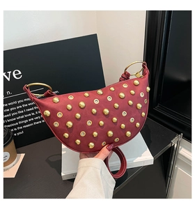 Detail of burgundy moon bag with gold ball studs and metal eyelets with ring handle