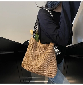 Detail of woven straw tote bag with black and white striped scarf on the handle