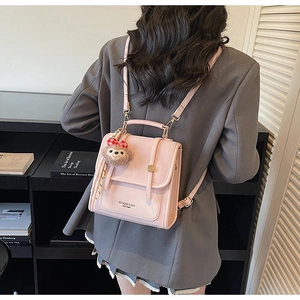 Detail view of the pink faux leather backpack with a decorative bow charm and metal clasp