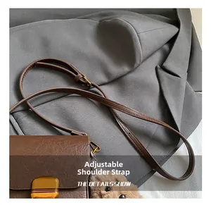 Detail of a brown leather crossbody bag featuring an adjustable strap and gold buckle
