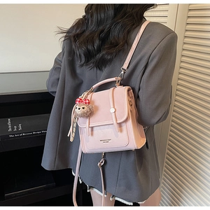 Detailed back view of a pink retro backpack with plush bear charm and leather straps