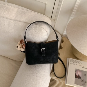 Detail of black suede bucket bag with silver metal buckle and cute teddy bear charm