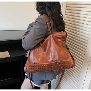 Detail of vintage caramel tote bag with silver studs on bottom and stylish tassels