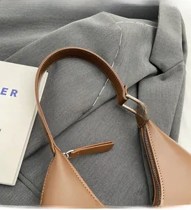 Détail de la poignée robuste marron caramel et des coutures sur le sac bandoulière croissant