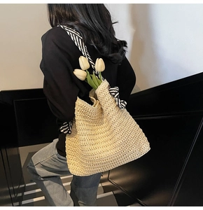Detail of straw shoulder bag featuring black and white striped ribbon and bow accent